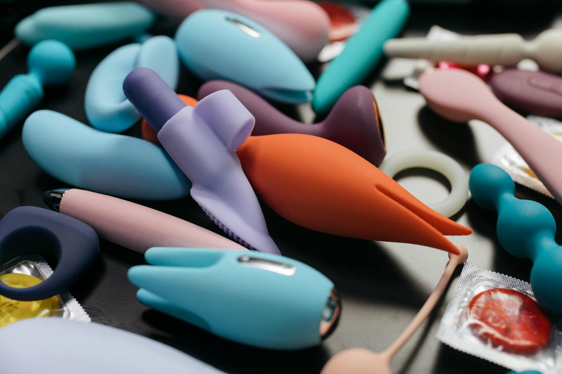 Two hands holding pink and blue silicone vibrators against a pastel background, symbolizing reconnection and shared pleasure