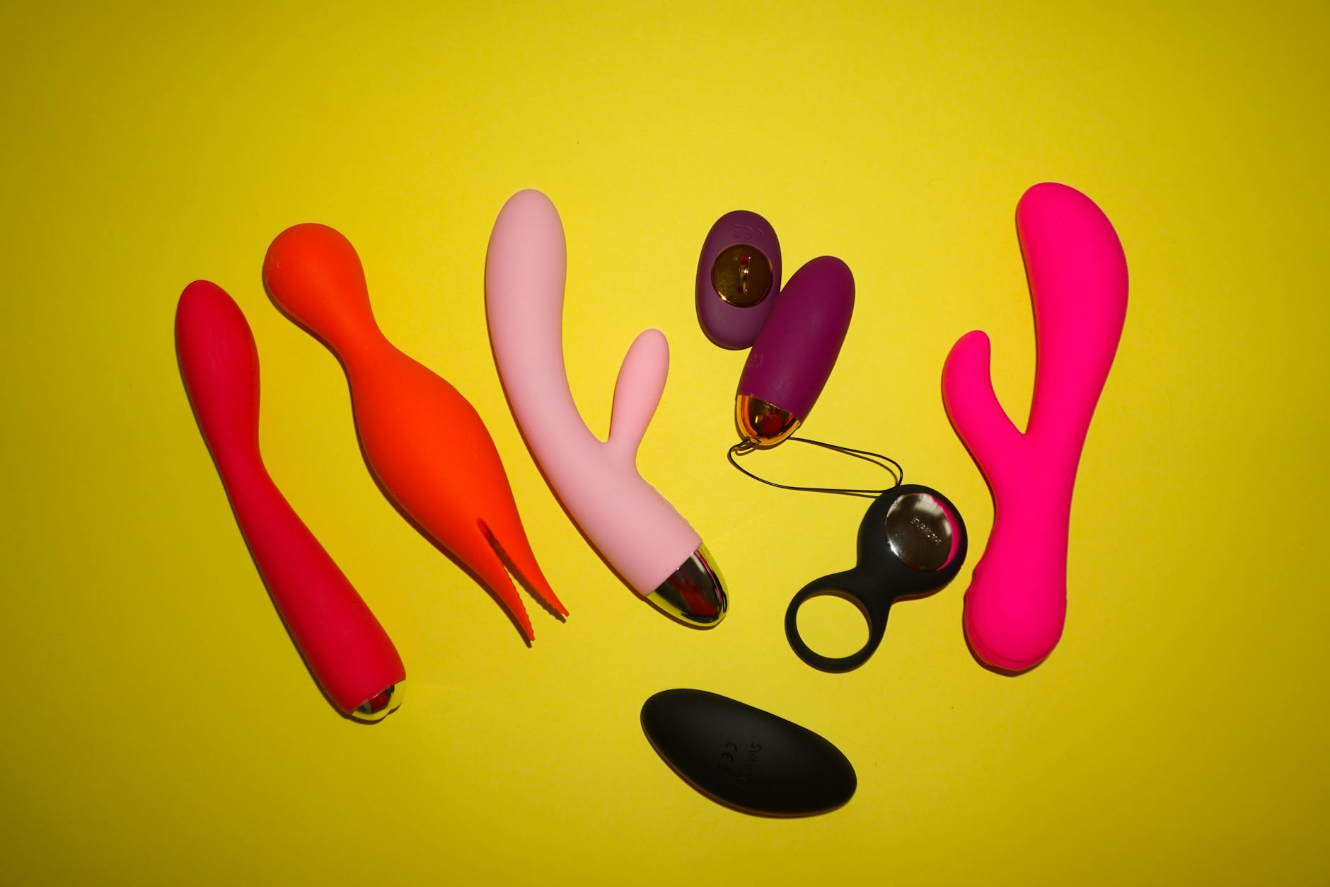 Yellow silicone vibrator on a bright yellow background with fresh lemons nearby