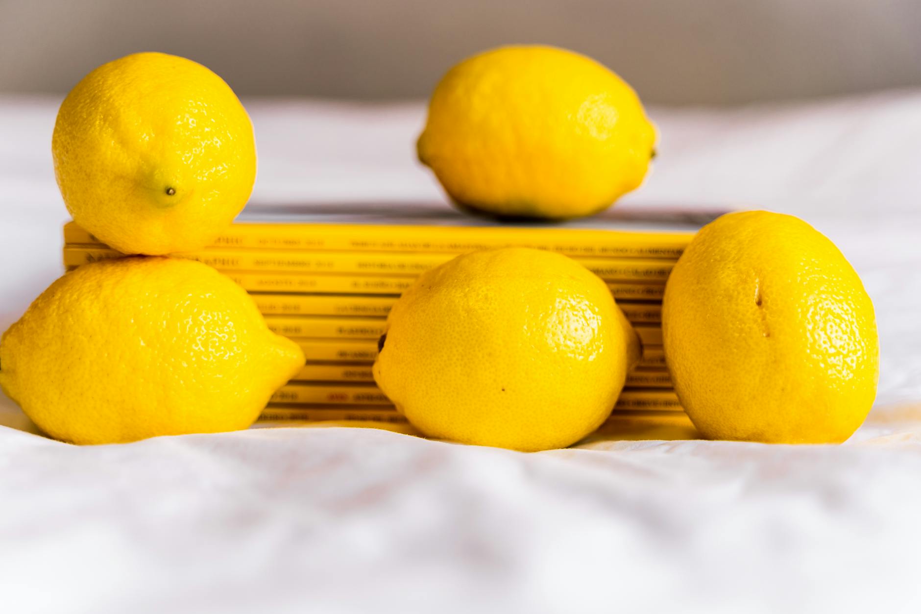 Hand holding a lemon on a soft pink background with gentle lighting